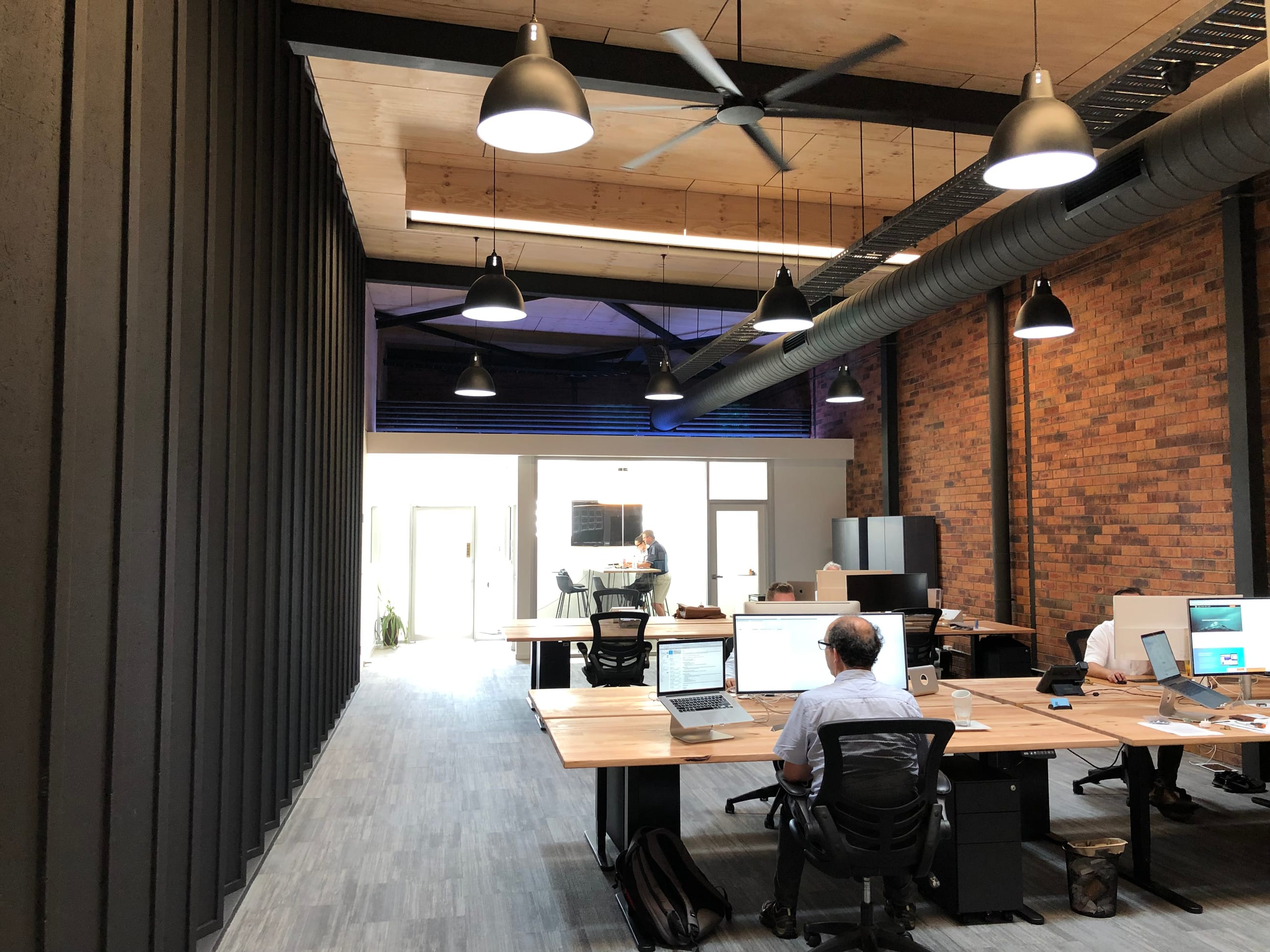 Inside the LittleMan studio — timber desks, exposed brick and pendant lights in a converted Newcastle warehouse, the team at work